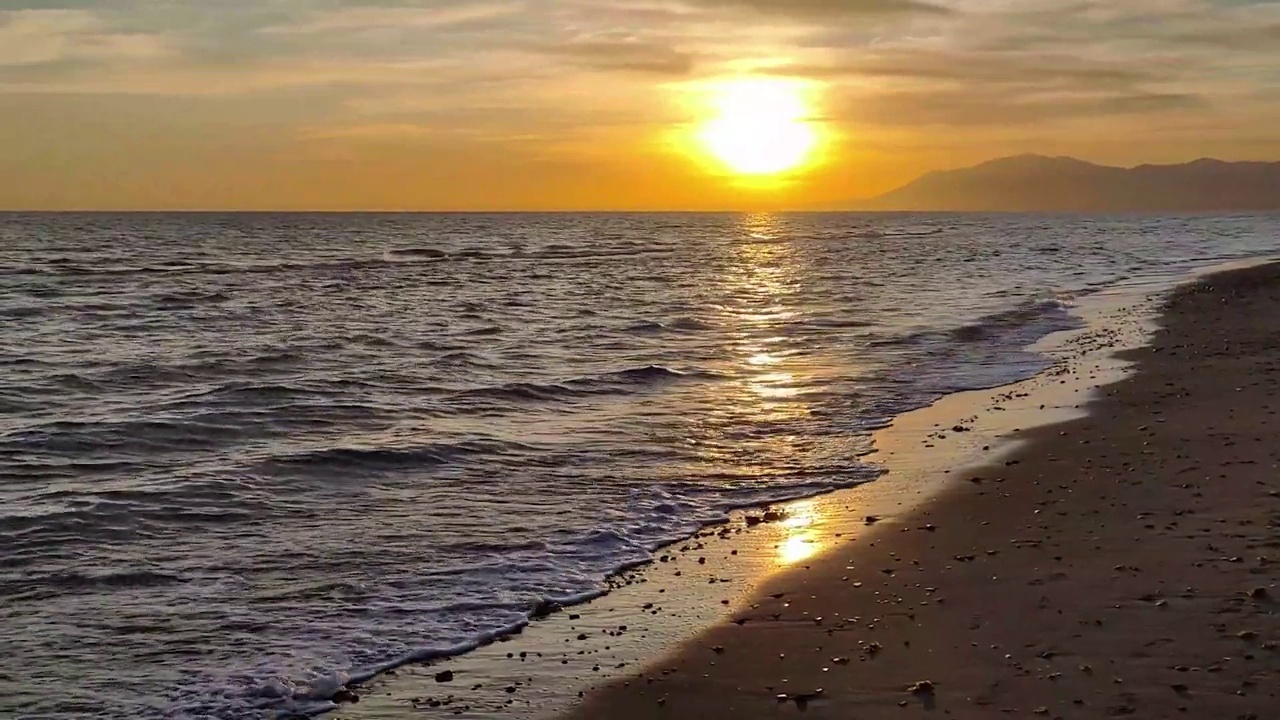 日落时海浪拍打着海滩视频素材