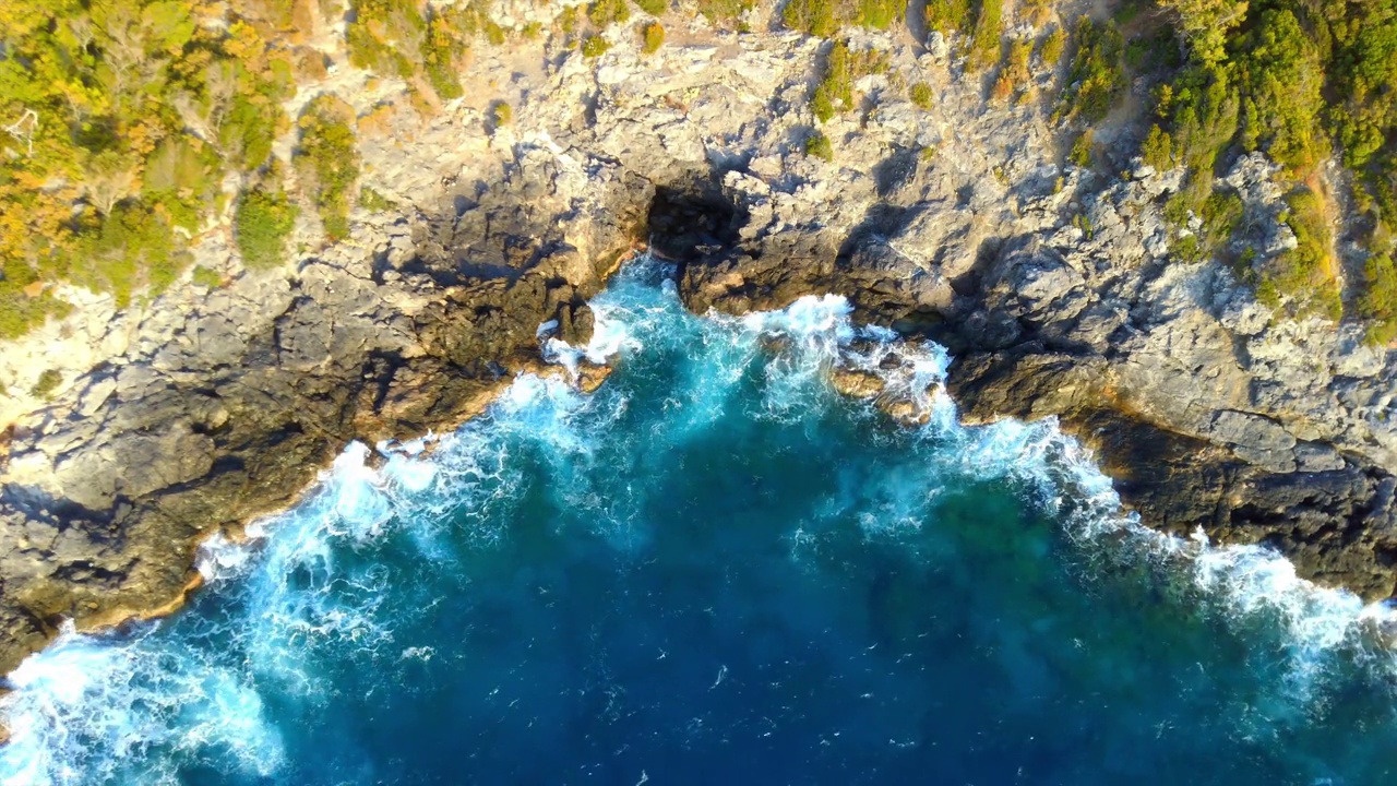 空中俯瞰蔚蓝的大海和海浪拍打着岩石悬崖视频素材