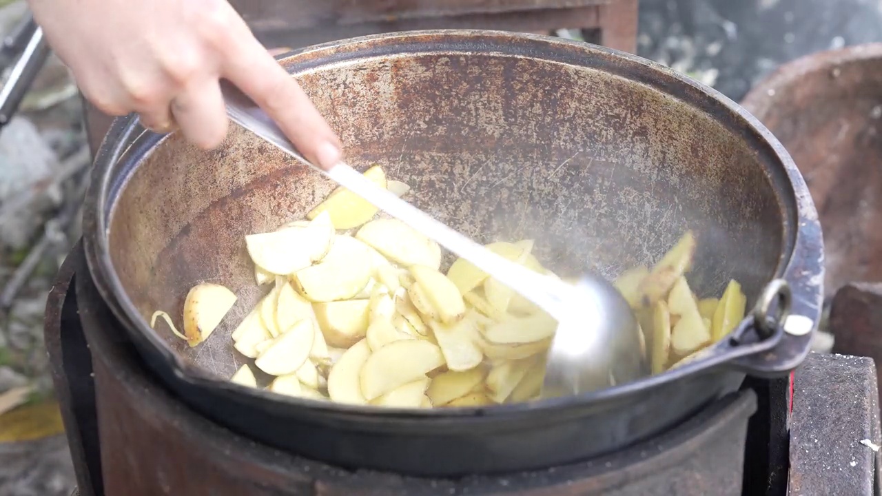 在自然的大锅里烹饪。厨师把炸土豆和洋葱混合在一起视频素材