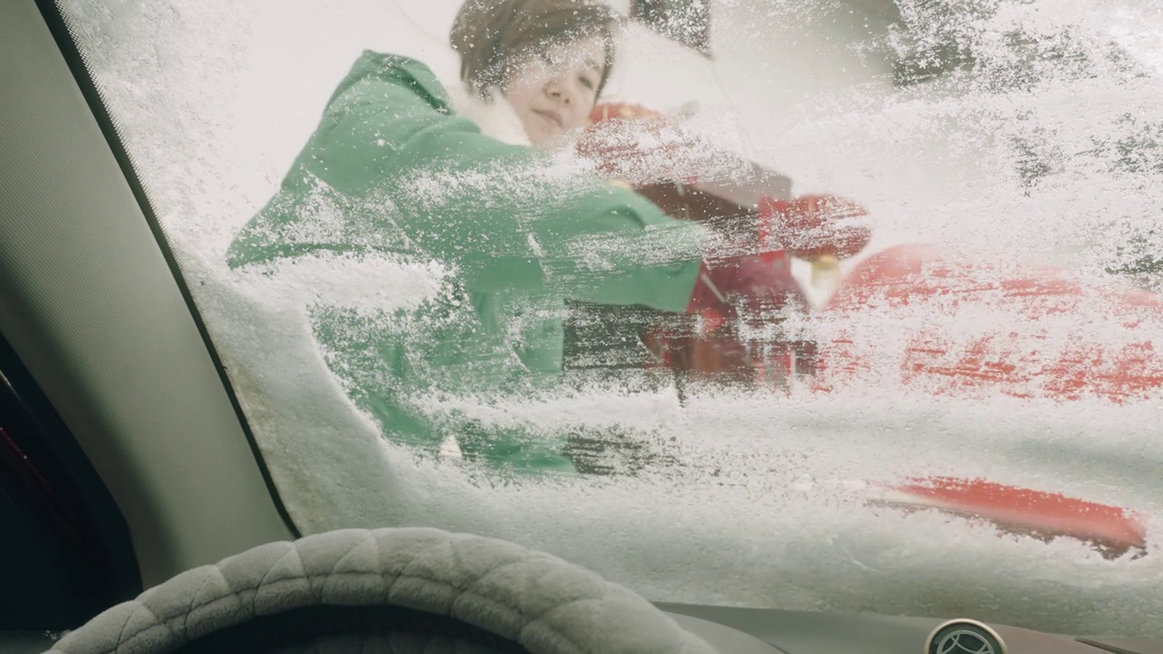 一个女人在刮汽车挡风玻璃上的雪。视频素材