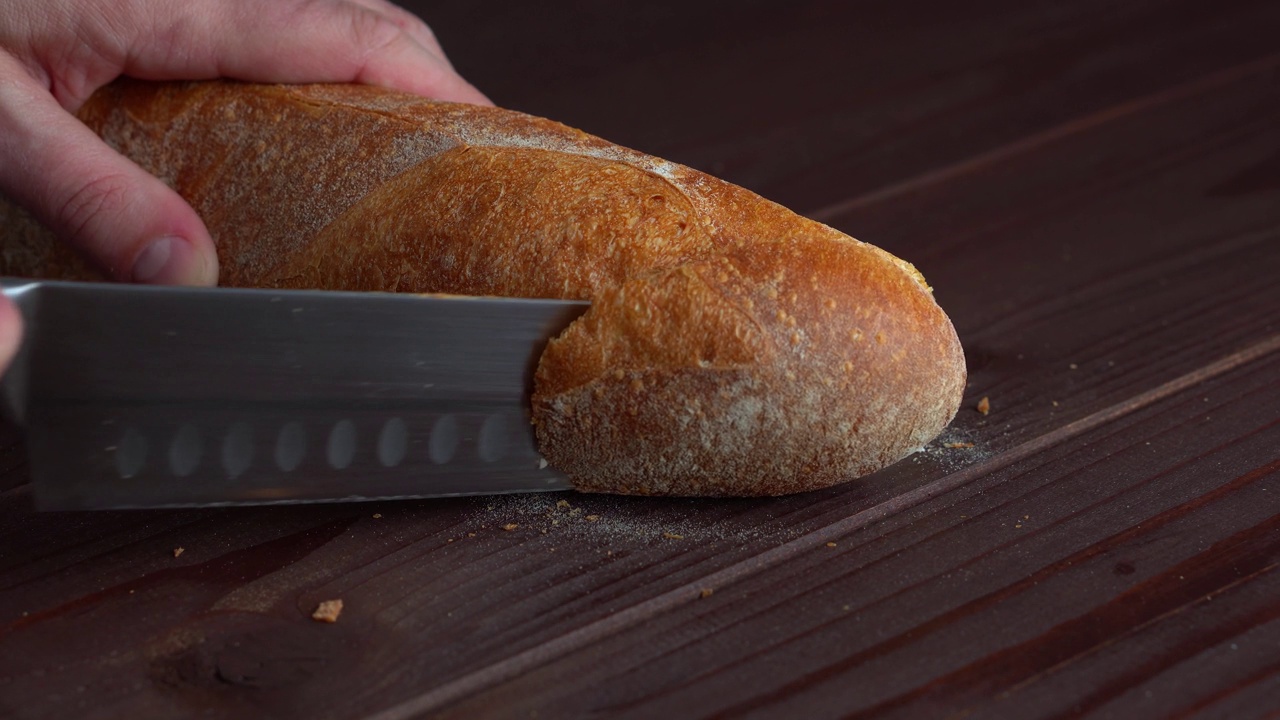 厨师在木板上用菜刀将自制的法式法棍面包切成片视频素材