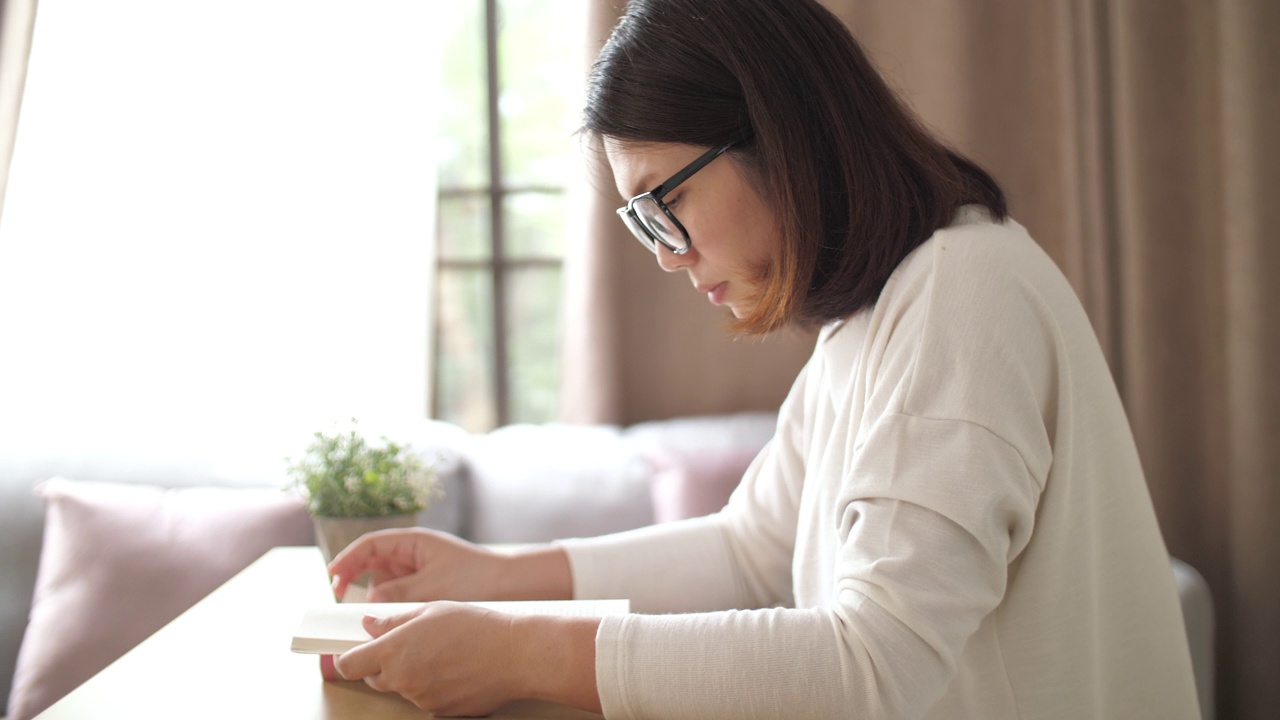 女人在家里的客厅里看书视频素材