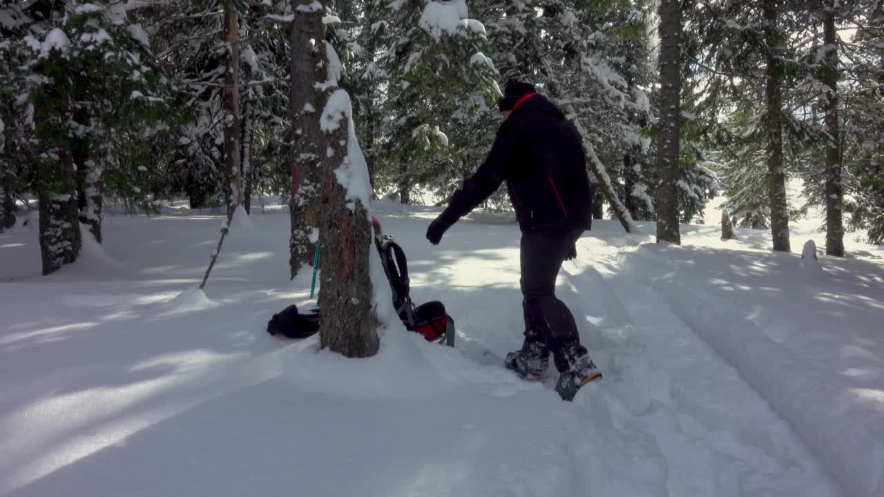 背着背包的徒步旅行者在积雪覆盖的冬季森林里行走视频素材