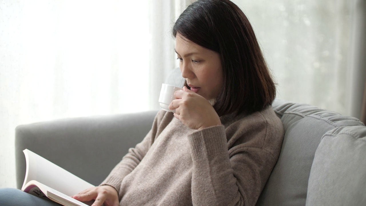 女人在家里的客厅里看书视频素材