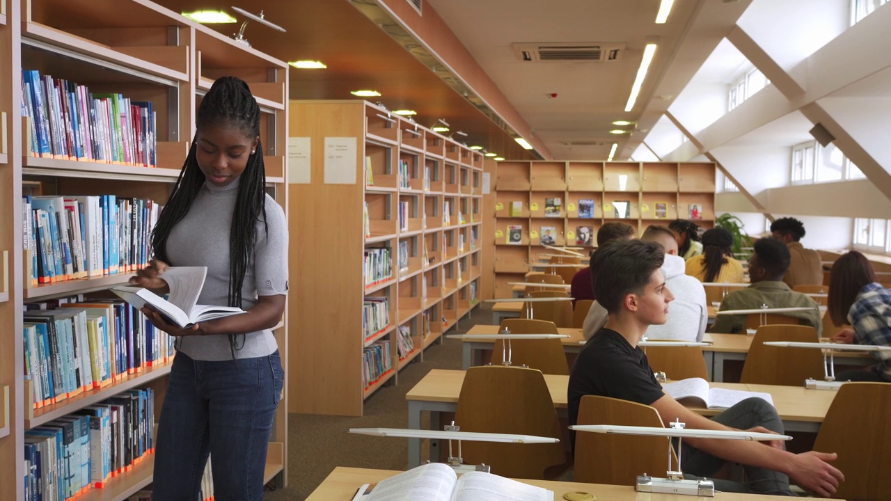 一位女学生正在现代大学图书馆里翻阅一本书视频素材