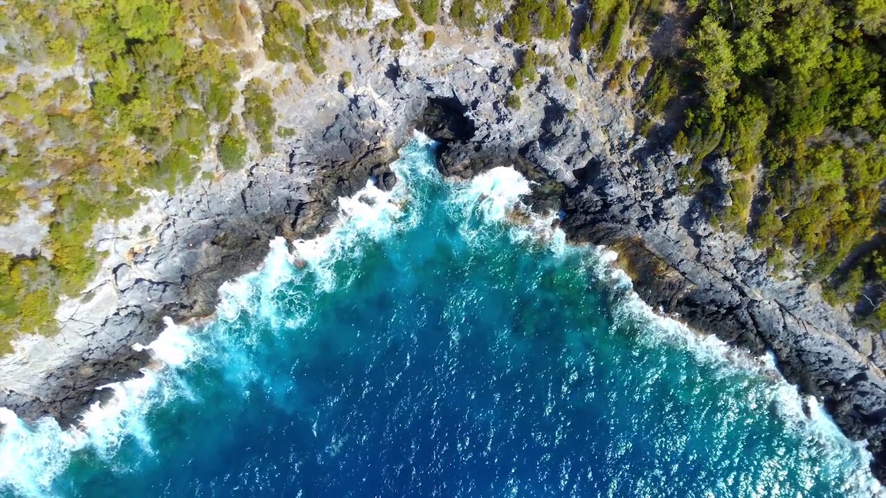 蔚蓝的海浪拍打着岩石峭壁的鸟瞰图视频素材