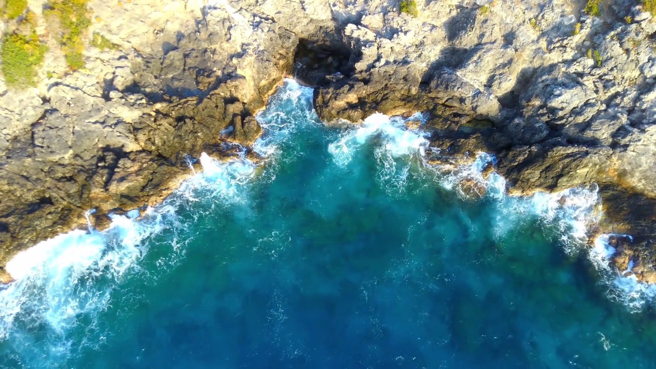 蔚蓝的海浪拍打着岩石峭壁的鸟瞰图视频素材