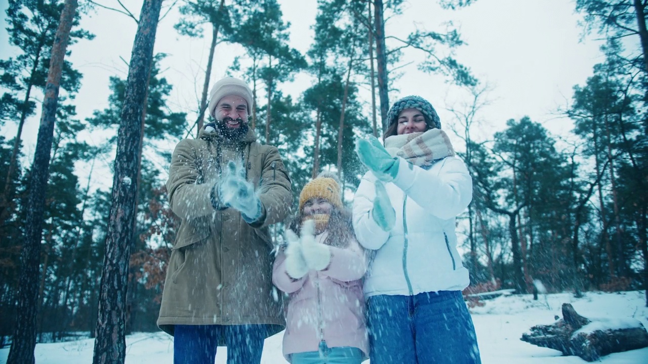 爸爸、妈妈和女儿笑着抖掉手套上的雪视频素材