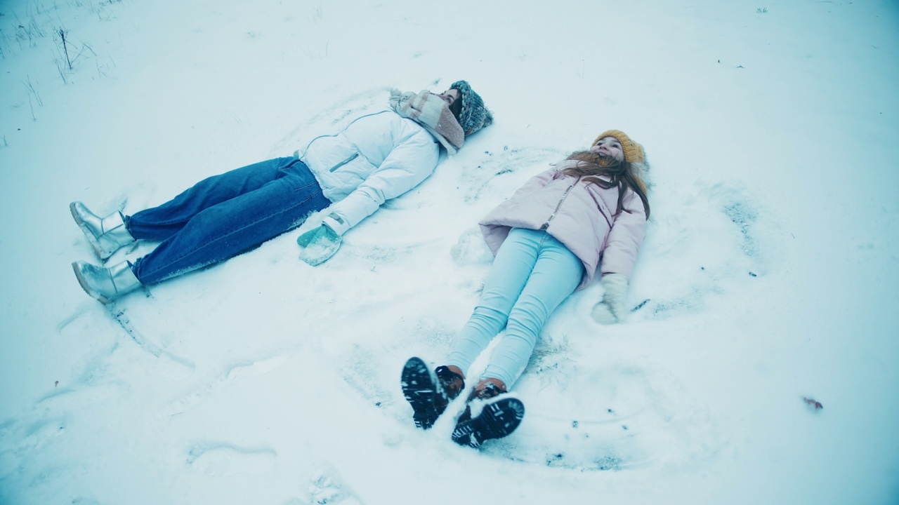 年轻的女人和女儿躺在地上做雪天使视频素材