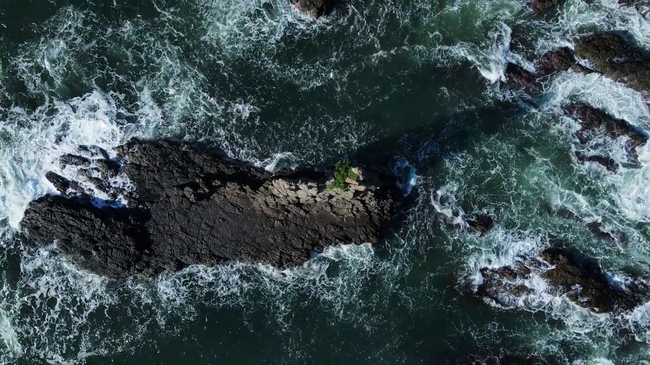 海浪冲破海岸岬上高耸的火山岩岩架的高视角。无人机的观点视频素材