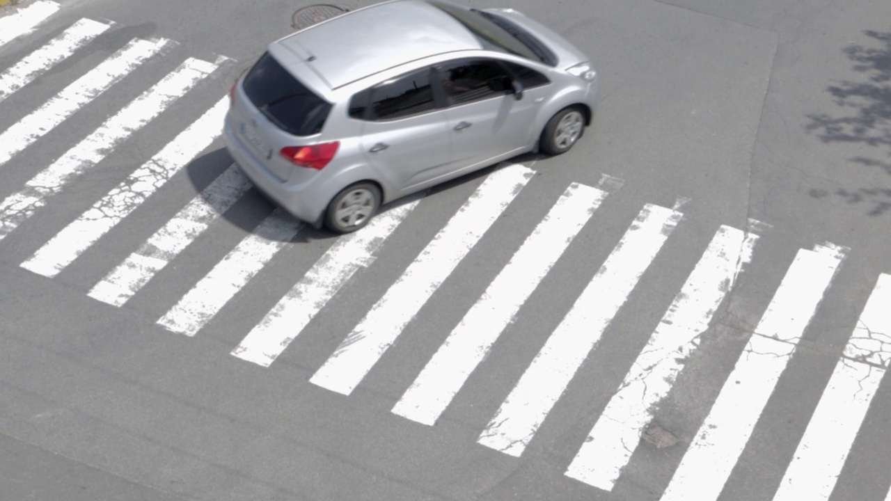 俯视图的汽车移动沿地面行人十字路口的道路。街上的汽车和斑马。城市景观。不受监管的人行横道。在十字路口操纵汽车视频素材