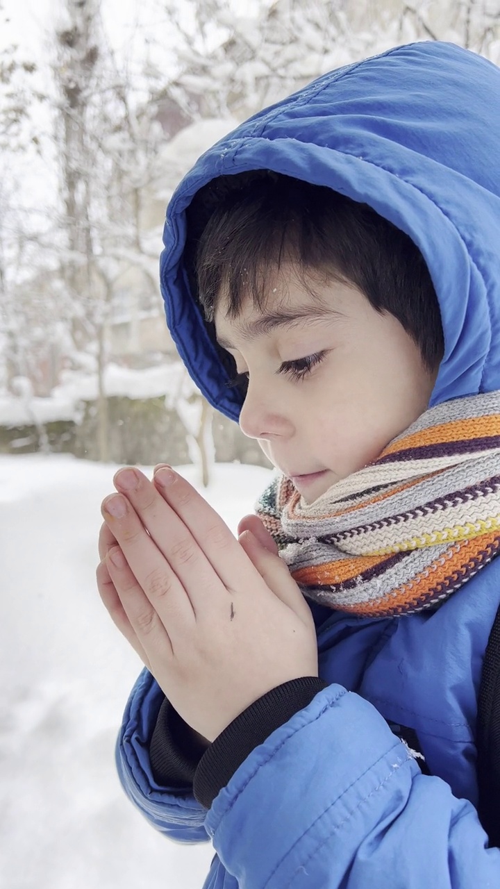 穿着蓝色冬衣的滑稽小男孩在下雪时行走。儿童冬季户外活动。视频素材