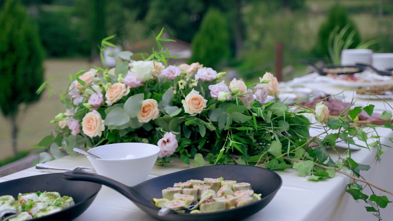 精美的宴会餐桌，新鲜的花束和各种食物放在盘子和木板上，为户外的官方仪式准备自助餐，豪华的庆祝派对，丰富的宴会餐桌菜单视频素材