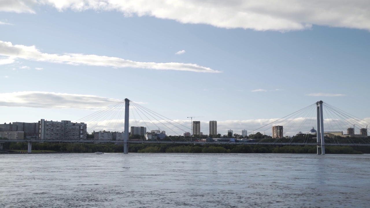 以城市桥下和城市的海岸线为背景，乘着摩托艇快速航行，城市的树木、购物中心和高楼大厦林立。享受在河上驾驶快艇的乐趣视频素材