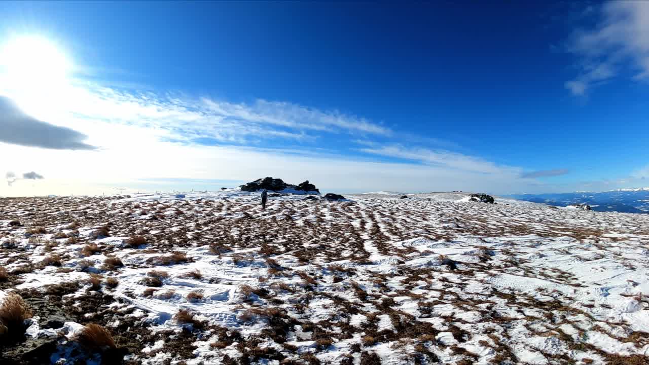 活跃的成年女性在奥地利卡林西亚和斯蒂利亚的拉万塔尔阿尔卑斯山的福斯塔佩山顶附近的积雪覆盖的高山草地上徒步旅行。Klipitztoerl的冬季仙境。徒步旅行路线视频素材