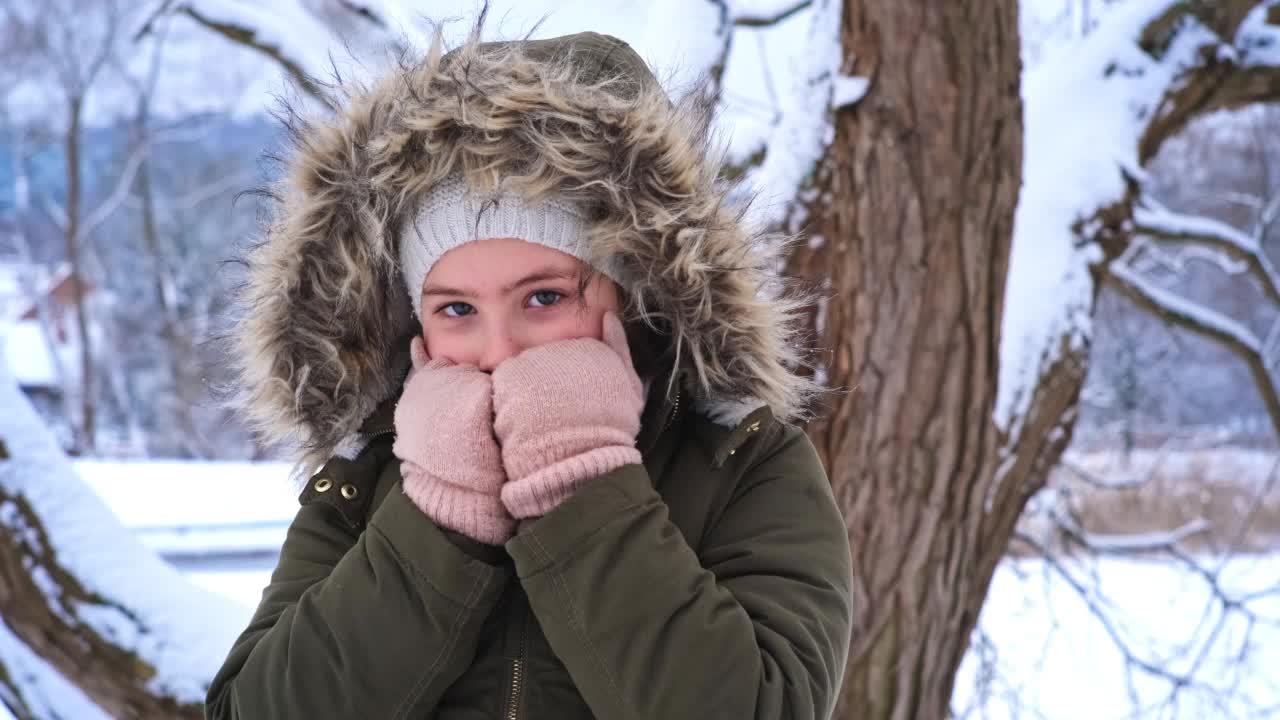 美丽的年轻高加索女孩在温暖的冬天夹克和手套站在户外寒冷的雪天视频素材