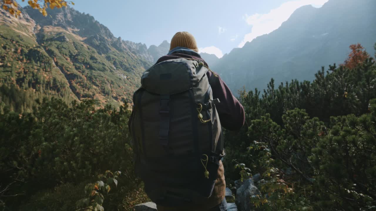 在阳光明媚的日子里，男性徒步旅行者徒步到美丽的山湖，俯瞰难以置信的高地景观。探险旅行探险者在塔特拉公园，莫尔斯基奥科湖视频素材