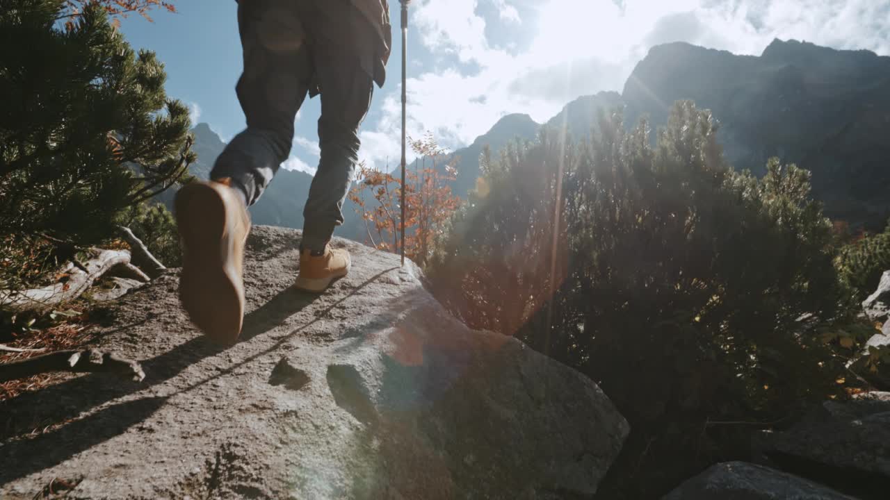 男徒步旅行者带着登山杖到达美丽的山湖。旅行者站在岩石上看令人难以置信的高地景观在阳光明媚的一天。在泰特拉公园探险旅行探险家视频素材