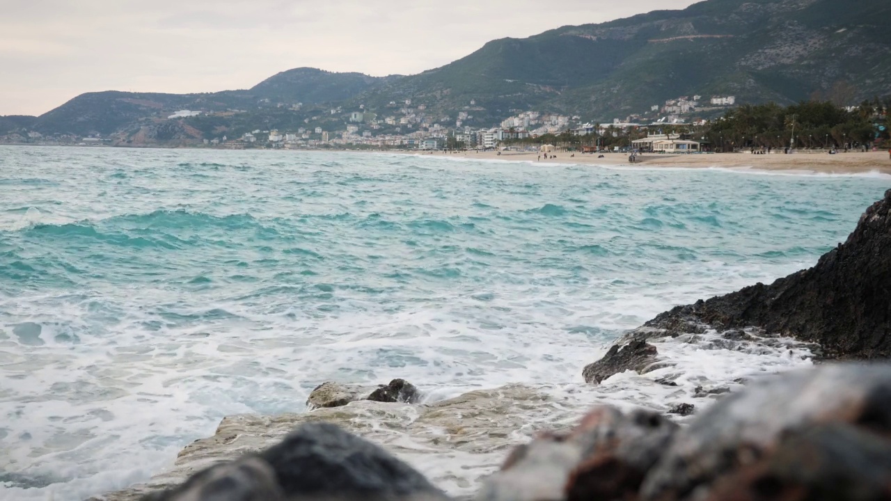 海浪冲击着岩石嶙峋的海岸线。湛蓝的海洋和巨大的海浪拍打着岩石悬崖，溅起白色的泡沫。蓝色的海浪拍打着岩石山脉的悬崖视频素材