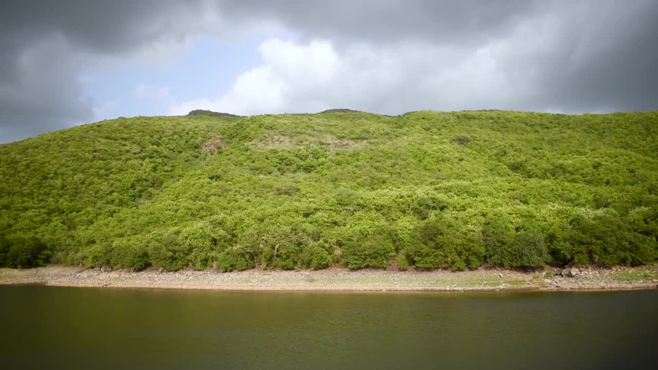 威灵顿大坝充满了水和郁郁葱葱的绿色吉纳尔山背景在朱纳加德，古吉拉特邦，印度。美丽的大自然在季风季节。季风的风景。视频素材