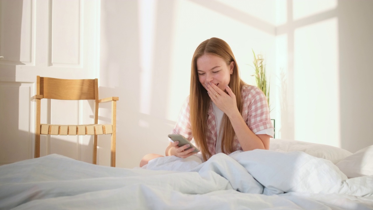 一个白人女孩一边用手机一边笑视频素材