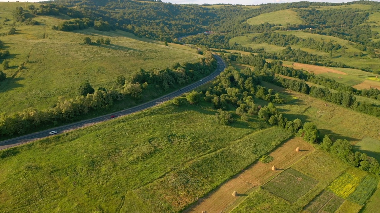 无人机在穿过高山草甸的道路上飞行。视频素材