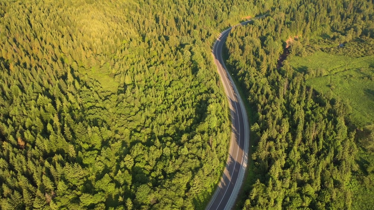 一架无人机在穿过山林的蜿蜒道路上飞行。视频素材