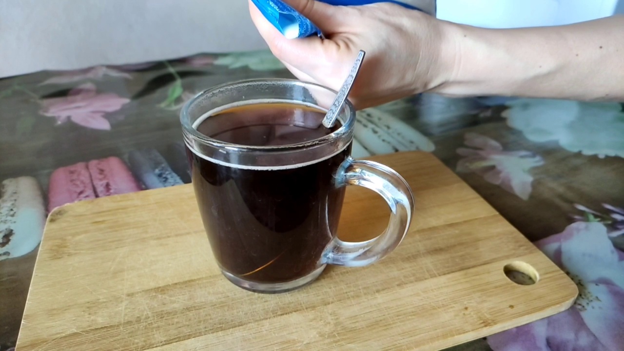 女人用一个透明的杯子往咖啡里倒牛奶，慢动作视频素材