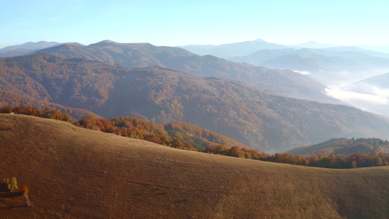 阳光明媚的一天，一架无人机飞过宁静的秋山。视频素材