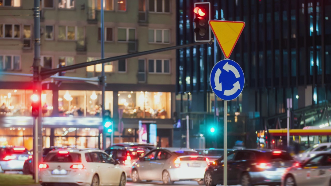 傍晚时分，疏景模糊了繁忙的城市道路标志和交通堵塞的车辆。市中心的交通高峰时间。难以辨认的汽车在夜间快速移动。前灯轨迹视频素材