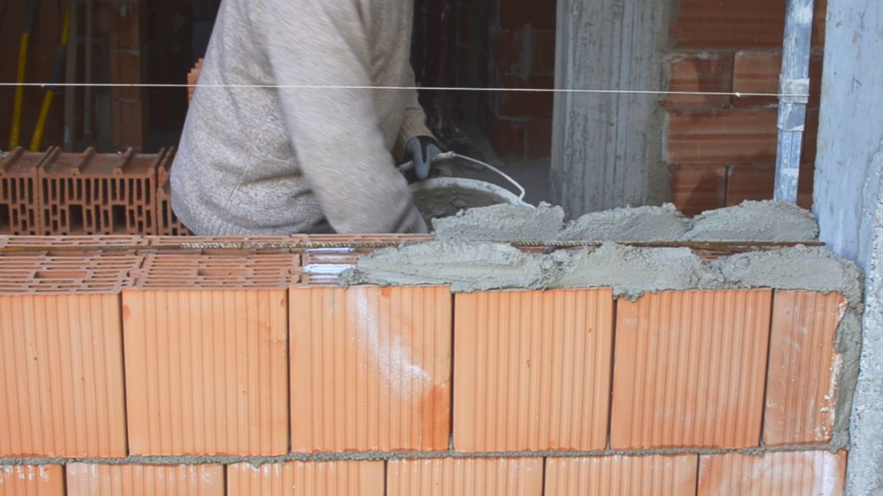 砌砖工人用抹刀和油灰刀在外墙砌筑砖视频素材