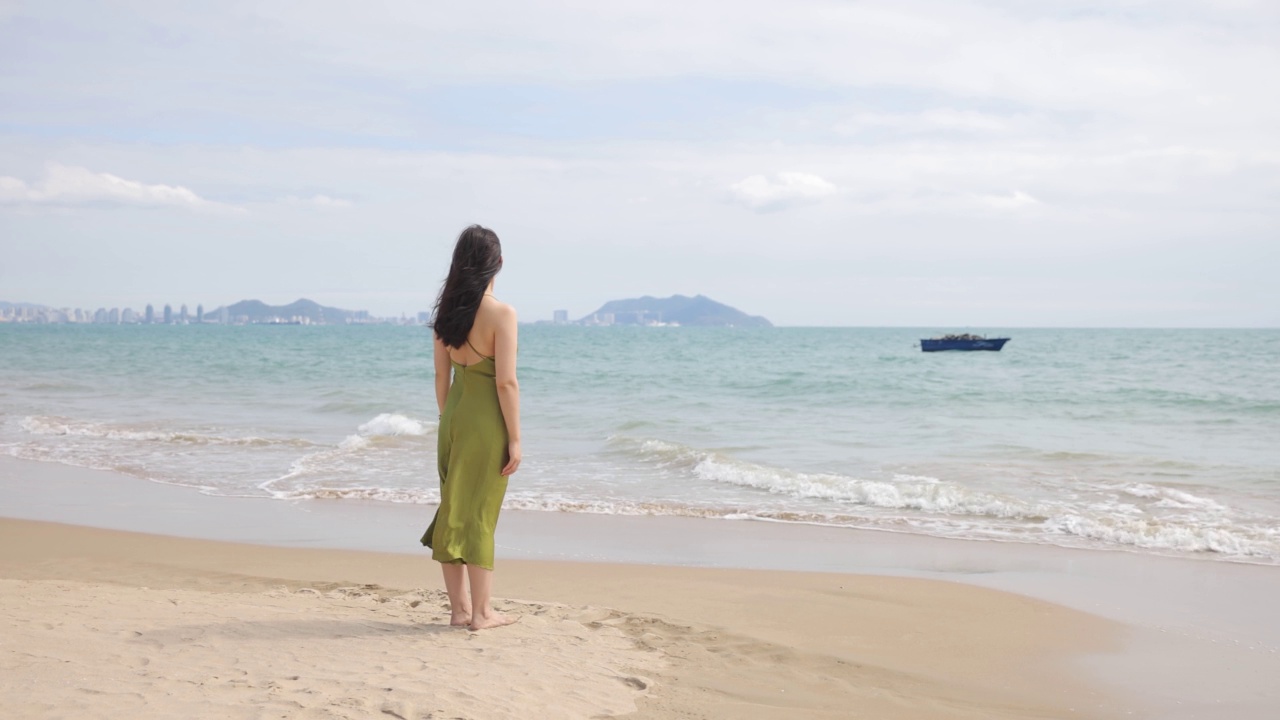 年轻女子站在沙滩上看海视频素材