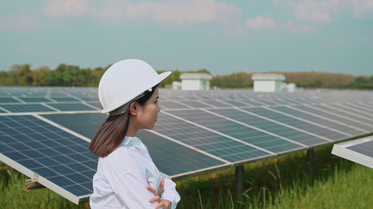 戴着头盔的女工程师在光伏电池场或太阳能电池板场，环保和清洁能源。视频素材