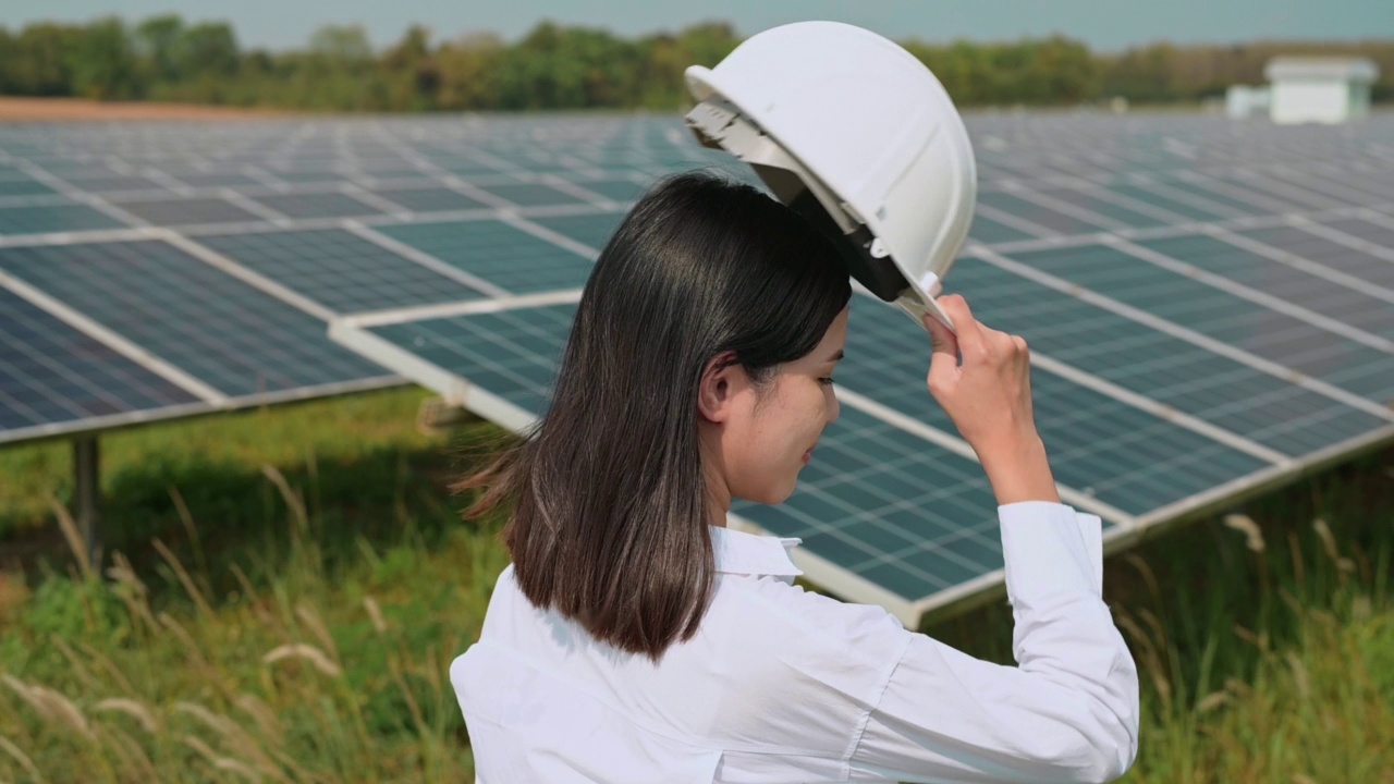 戴着头盔的女工程师在光伏电池场或太阳能电池板场，环保和清洁能源。视频素材