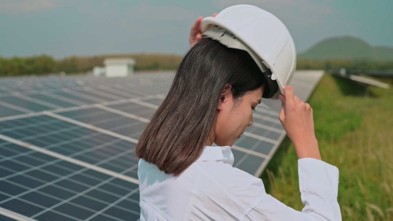 戴着头盔的女工程师在光伏电池场或太阳能电池板场，环保和清洁能源。视频素材