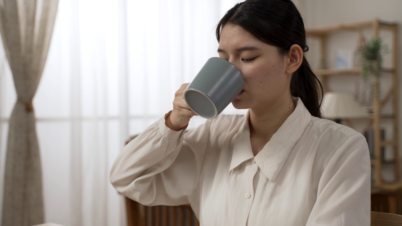 这是一位韩国女企业家在家中客厅边喝茶边用电脑工作的特写视频素材