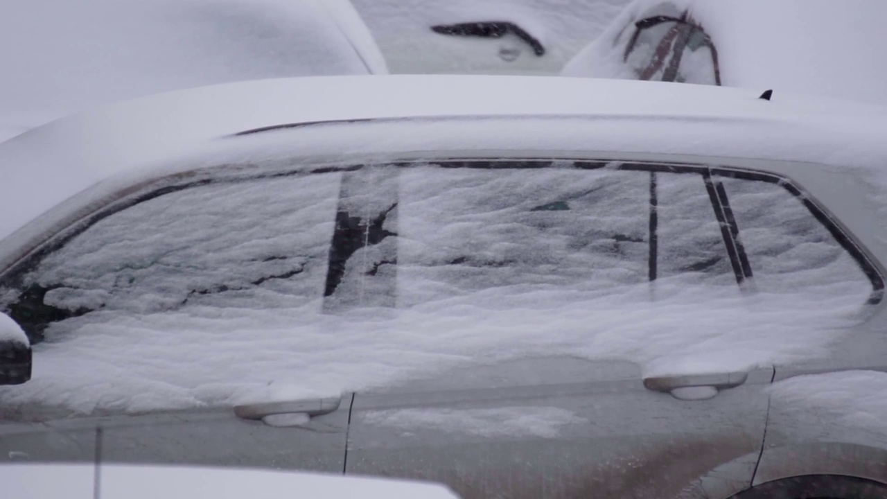 冬季停车场积雪覆盖的汽车在白天降雪慢镜头。有选择性的重点视频素材