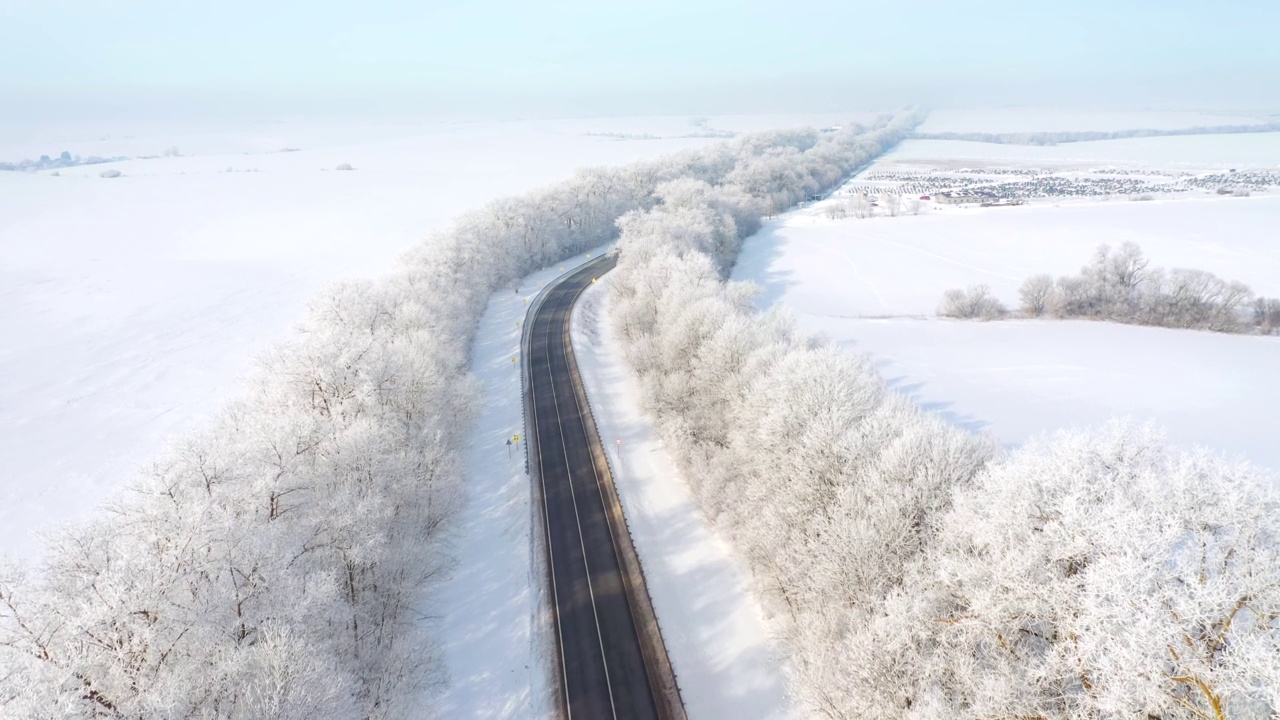 在阳光明媚的日子里，无人机会飞过雪地里的高速公路。视频素材