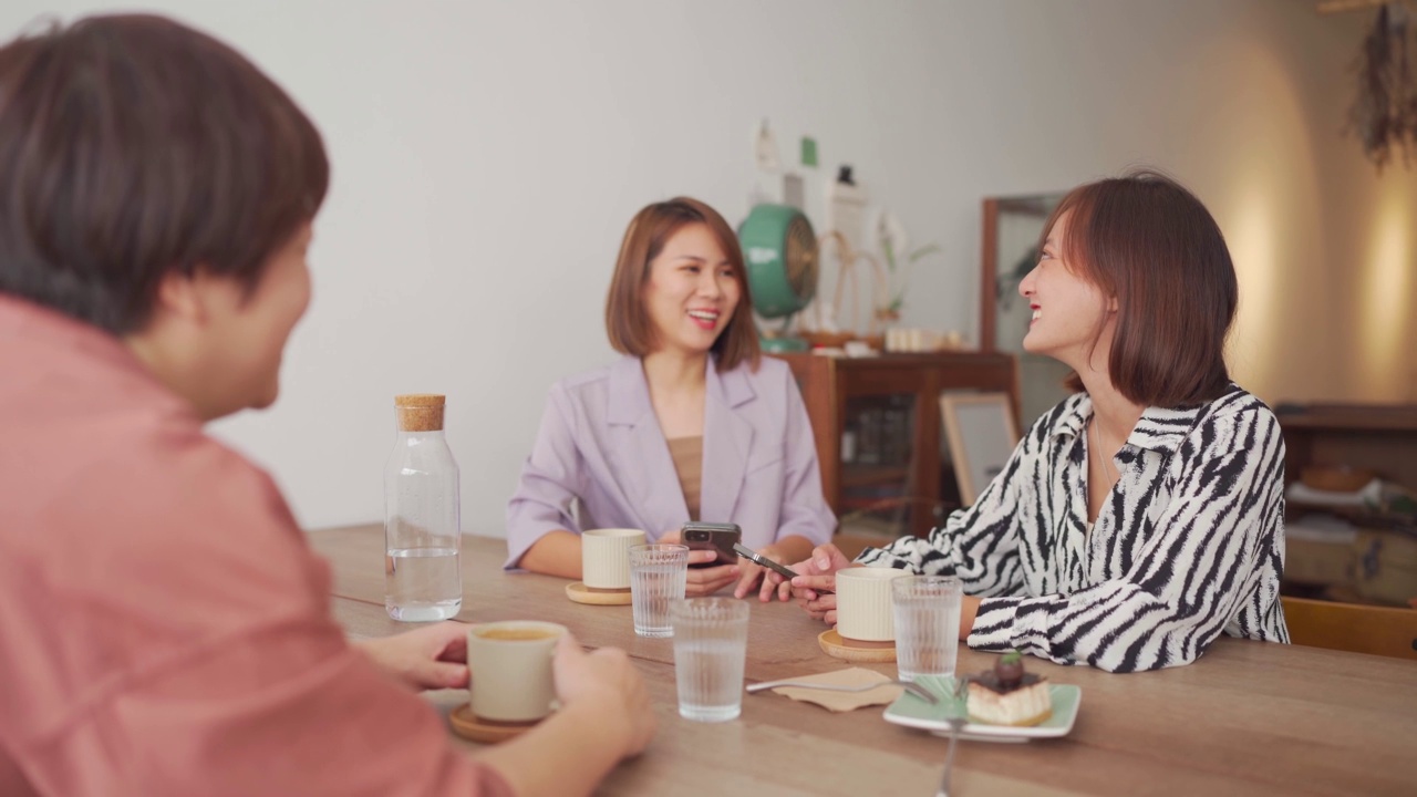 亚洲华人女性享受咖啡休息，在咖啡馆社交聚会，聊天，使用智能手机视频素材