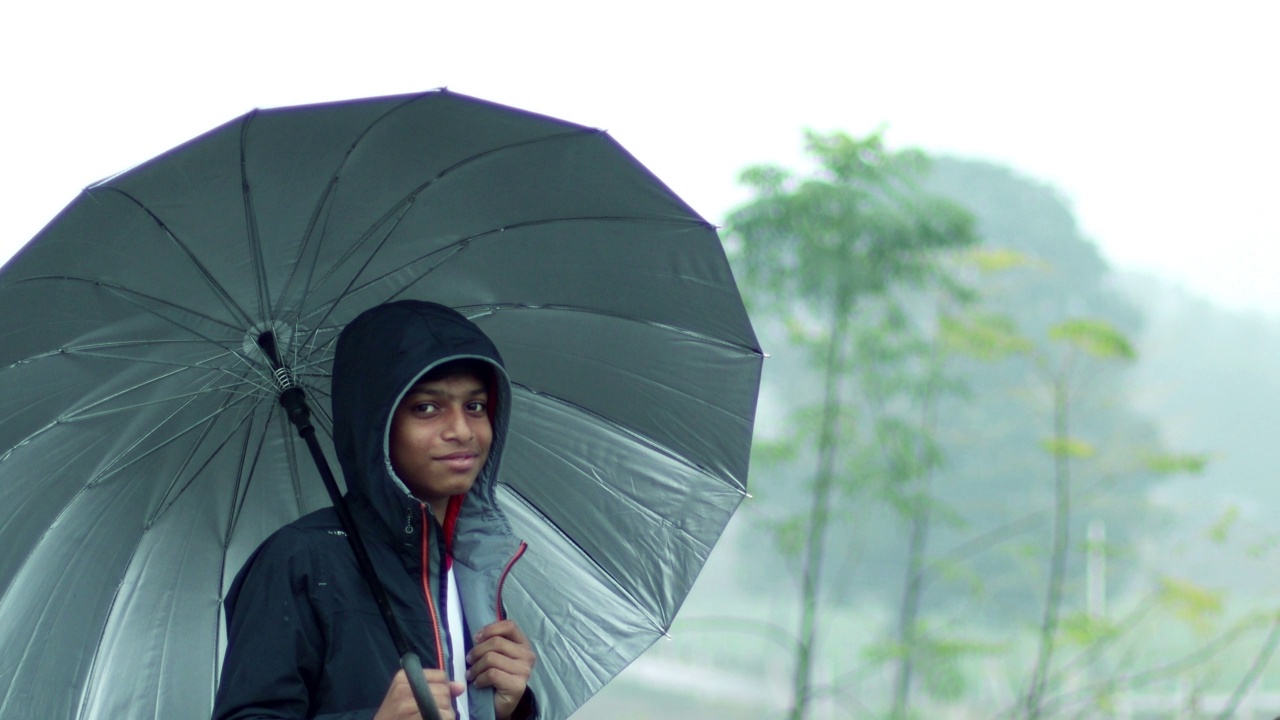 在雨季，十几岁的男孩站在户外的自然背景下视频素材