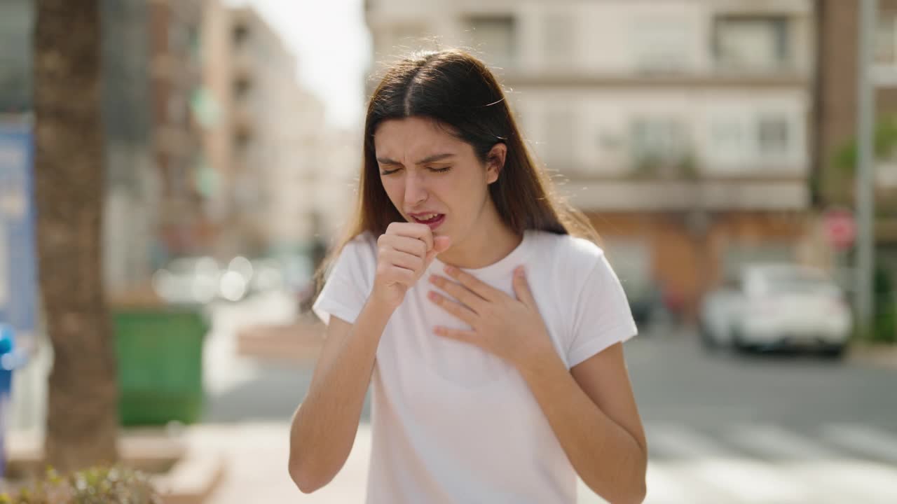 年轻的西班牙女孩在街上咳嗽视频素材