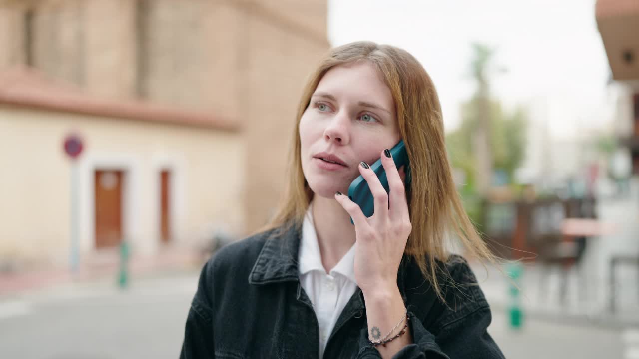 年轻的白人女性微笑着自信地在街上用智能手机说话视频素材