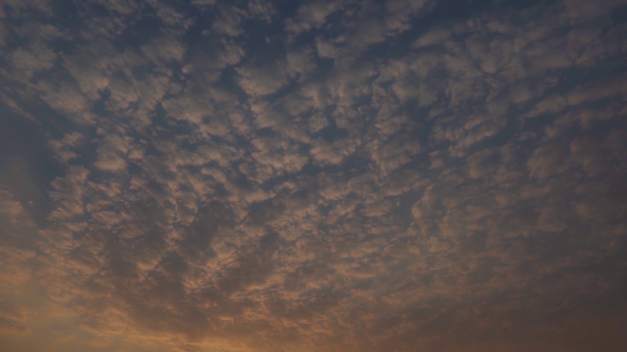 日落时天空中的云的全景式镜头。乌云在日落时形成背景。日落时云变成橘黄色。视频素材