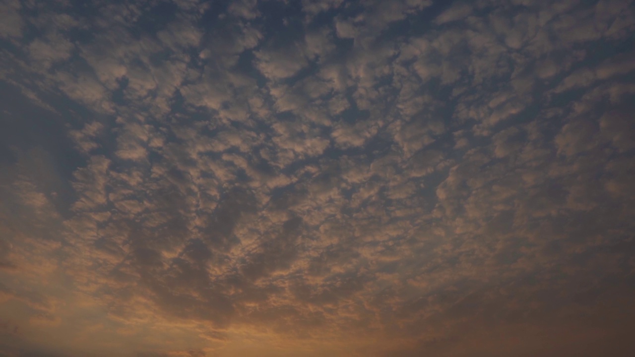 日落时天空中的云的全景式镜头。乌云在日落时形成背景。日落时云变成橘黄色。视频素材