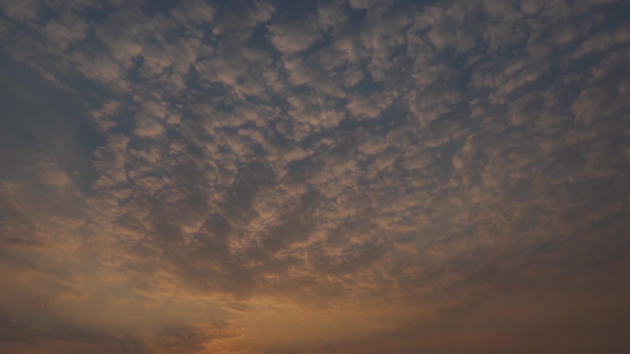 日落时天空中的云的全景式镜头。乌云在日落时形成背景。日落时云变成橘黄色。视频素材