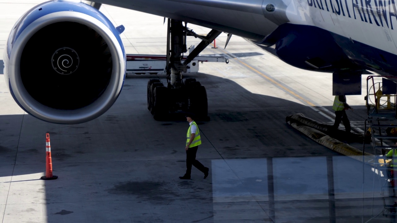 4k英国航空公司飞行员在飞行前起飞检查的维护检查程序中检查飞机的跟踪镜头。飞行员在批准前检查飞机货物装载、机身下、发动机和机翼视频素材