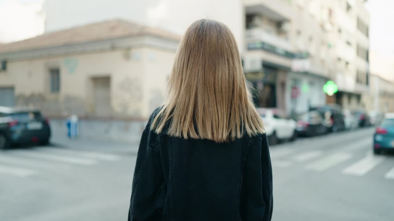 年轻的白人妇女微笑着自信地站在街上，双手交叉的姿势视频素材