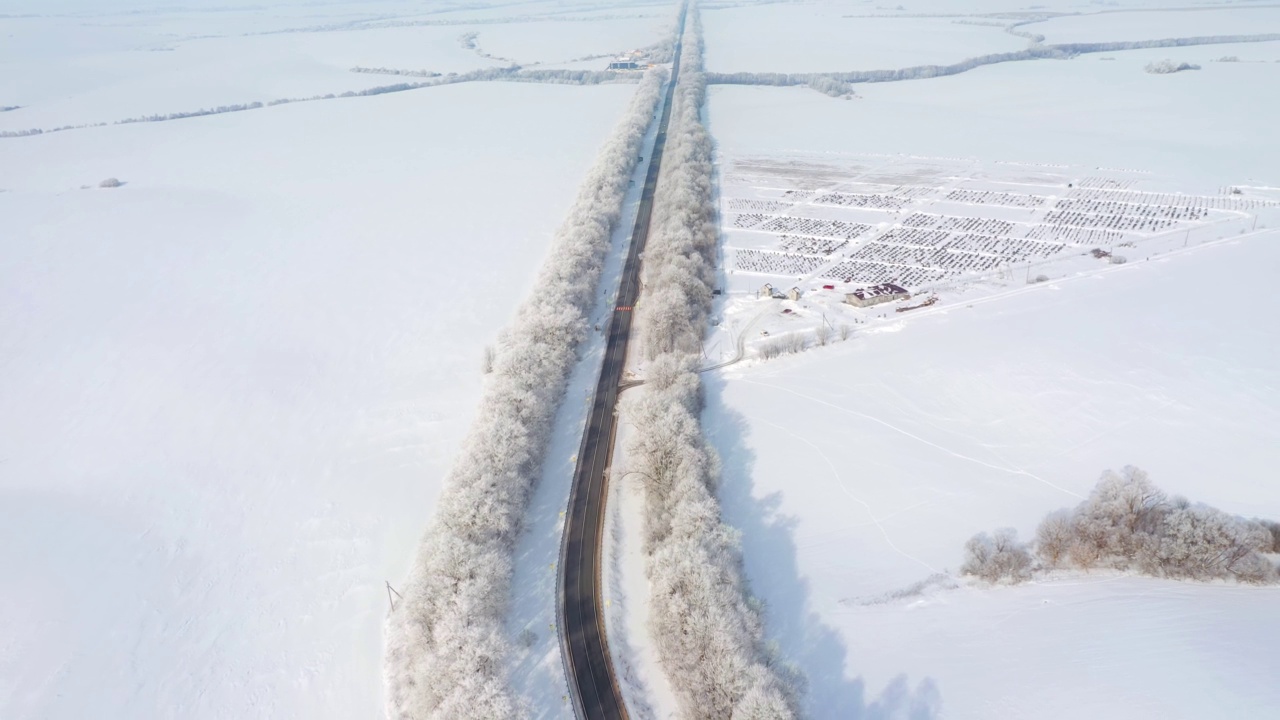 在阳光明媚的日子里，无人机会飞过雪地里的高速公路。视频素材