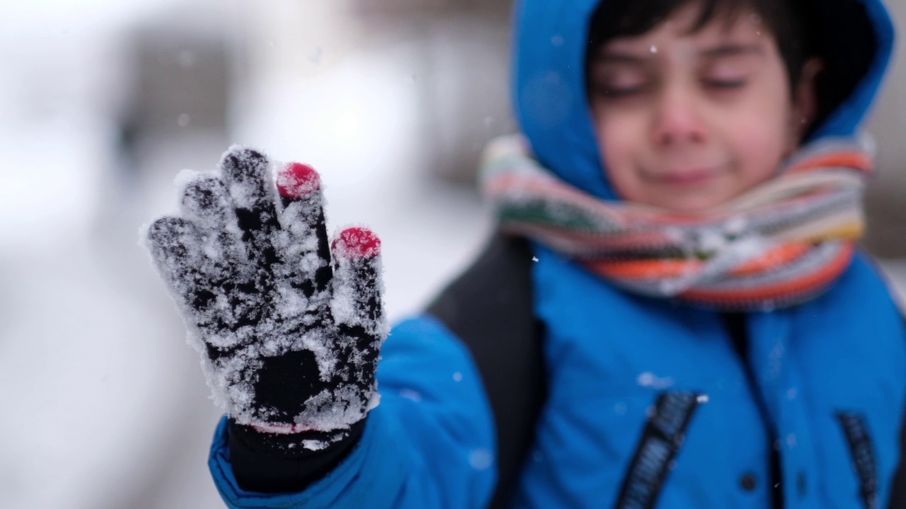 穿着蓝色冬衣的有趣小男孩在下雪的时候散步。视频素材