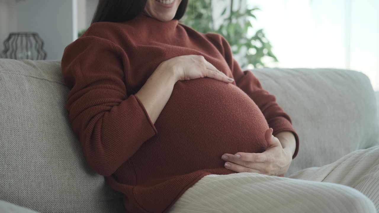 孕妇在沙发上抚摸自己的肚子视频素材